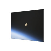 A gibbous moon visible above Earth's atmosphere Canvas Prints