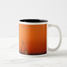 A Giraffe couple walks into the sunset, in Coffee Mugs
