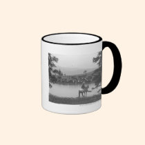 Cattle by a pond with two cowboys. mugs