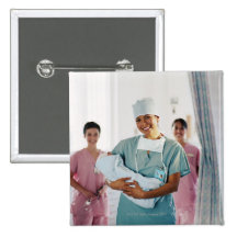 Delivery room nurse holding baby, nurses in pinback buttons