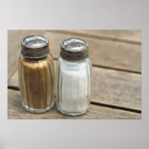Salt-cellar and pepper-caster on wooden table poster