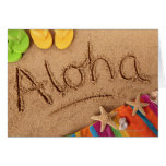 The word Aloha written on a sandy beach, with 2 Card