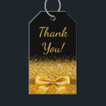 16th birthday party black gold bow thank you gift tags<br><div class="desc">Elegant,  classic,  glamourous and feminine style gift tag,  favour tag.  A gold coloured ribbon and bow with golden glitter and sparkle,  a bit of bling and luxury for a 16th birthday party.  Black background. With the text: Thank You! on front.
Back: Templates for name and age 16.</div>