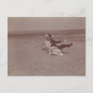 2 people at beach losing hats postcard