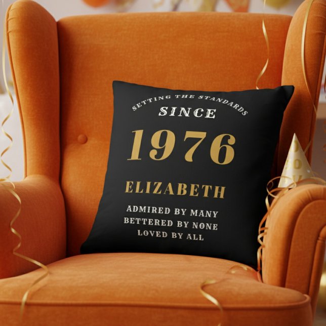 50th Birthday Gift Personalized 1976 Black Gold Cushion (Personalized 50th birthday pillow on a vibrant orange velvet wingback chair)