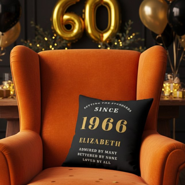 60th Birthday Gift Personalized 1966 Black Gold Cushion (A personalized black pillow on a vibrant orange velvet wingback armchair )