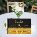 70th birthday black gold classic elegance guest book<br><div class="desc">Elegant,  classic,  glamourous and feminine.  A gold coloured ribbon with a bow with golden glitter and sparkle,  a bit of bling and luxury. A guestbook for a 70th birthday party. Black background. Templates for name,  age,  date of birth and anniversary date. Spine: add name and date.</div>