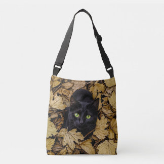 A black cat is playing in the autumn leaves crossbody bag