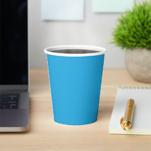 a blue background with a black and white cat on to paper cups