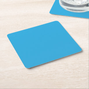 a blue background with a black and white cat on to square paper coaster
