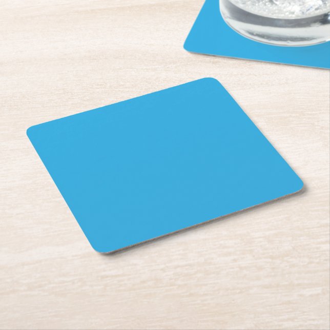 a blue background with a black and white cat square paper coaster (Angled)