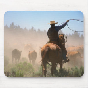 A cowboy out working the herd on a cattle mouse pad