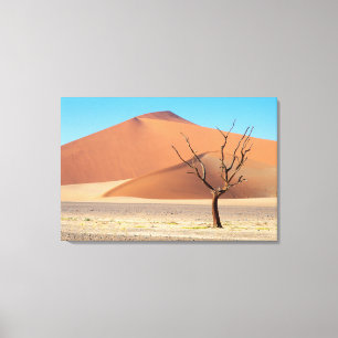 A dead tree on a desert plain with dunes canvas print