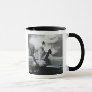 A flight deck director signals an F/A-18F Mug