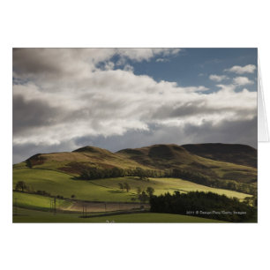 A Landscape With Rolling Hills And Clouds Overhead