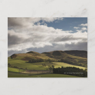 A Landscape With Rolling Hills And Clouds Overhead Postcard