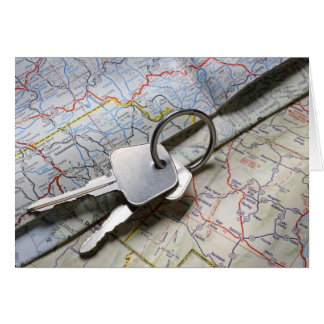 A set of car keys on a pile of road maps.