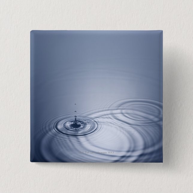 A single droplet of water falling into a calm 15 cm square badge (Front)