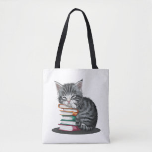 A sleepy kitten cuddled up with a stack of books. tote bag