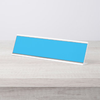 A vibrant blue sky with a few scattered white clou desk name plate