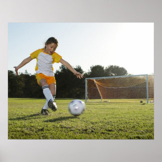 A young girl playing soccer on a soccer field in poster