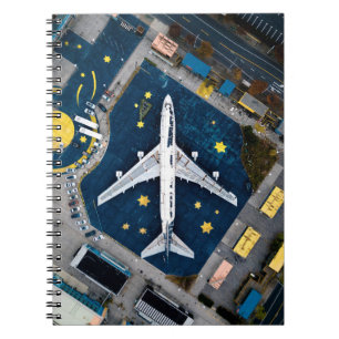 AERIAL PHOTOGRAPHY OF WHITE AND BLACK AIR LINER ON NOTEBOOK