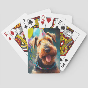 Airedale dog with birthday hat and balloons playing cards