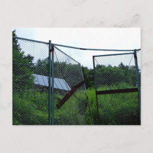 An abandoned house beyond the broken fence. postcard