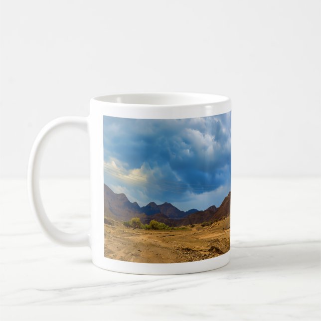 An arid landscape under a dramatic, cloudy sky coffee mug (Left)