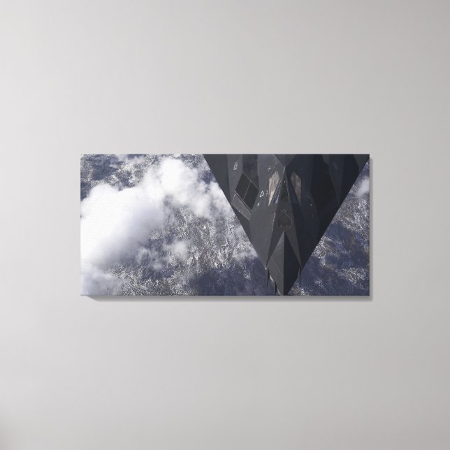An F-117A Nighthawk flies high over the mountai Canvas Print (Front)