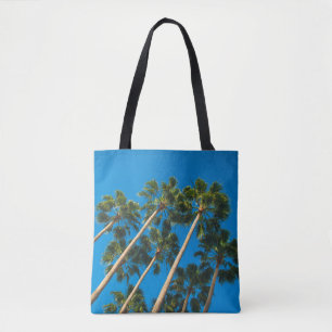 Angle perspective of group of tall thin palm trees tote bag