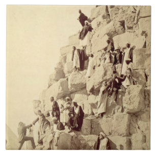 Arabs assisting tourists to climb the pyramids at tile