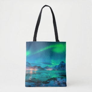 Aurora borealis over the sea coast, snowy mountain tote bag