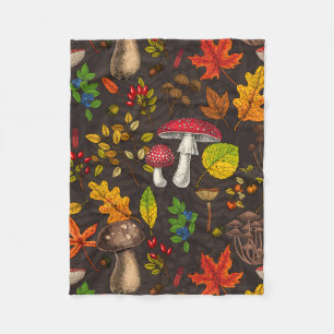 Autumn mushrooms, leaves, nuts and berries on dark fleece blanket