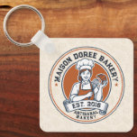 Bakery Store Pastry Chef Dessert Sweets Cake Baker Key Ring<br><div class="desc">This vintage-style circular logo features a cheerful female pastry chef wearing a traditional white chef's hat and apron. She is framed by a warm orange circular backdrop and holds a wire whisk in one hand and a flaky croissant in the other, symbolizing her culinary expertise. Below her, a blank, elegant...</div>
