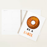 Be a Bagel Funny Food Pun Bagel Lover Design  Planner<br><div class="desc">Stay organised with a touch of humour using this “Be a Bagel” spiral planner. Featuring a fun bagel illustration and a witty pun, this planner is perfect for food lovers, brunch enthusiasts, and anyone who enjoys quirky designs. With a durable spiral binding and high-quality pages, it’s ideal for keeping track...</div>