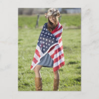 Beautiful cowgirl wrapped in American flag