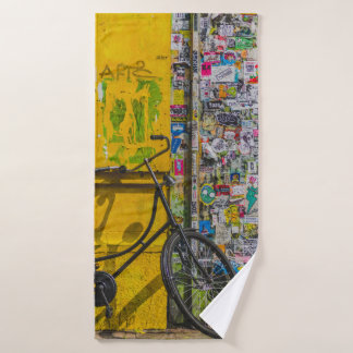 BIKE PARKED BESIDE WALL FULL OF STICKERS BATH TOWEL