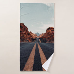 BLACK ASPHALT ROAD BETWEEN BROWN ROCK FORMATION UN BATH TOWEL