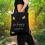 Black bee happy bumble bees summer yellow name tote bag<br><div class="desc">Decorated with happy,  smiling yellow and black  bumblebees. A chic black background. White hand lettered script and the text: Bee Happy.  Personalise and add your name.</div>