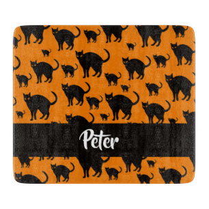 Black cats on orange cutting board