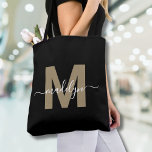 Black Gold Trendy Modern Script Name Monogram Tote Bag<br><div class="desc">Personalised Elegant Black Gold Trendy Modern Script Name Monogram Tote Bag. Add a touch of glamour and sophistication to your everyday style with this chic tote bag. Featuring a sleek gold initial (note: the gold is a flat colour, with no shimmer or foil) centred on a crisp black background, and...</div>