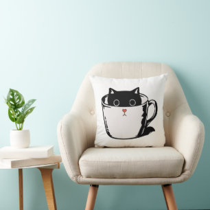 Black kitten with red nose hiding in a cup cushion
