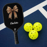 Black leopard bow name pickleball paddle<br><div class="desc">Black background,  decorated with a bow with leopard print. Soft pink background. Personalise and add your name. White text.</div>