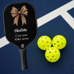 Black leopard bow name quote pickleball paddle<br><div class="desc">Black background,  decorated with a bow with leopard print. Soft pink background. Personalise and add your name. White text. Quote: Cute bow. Killer serve</div>