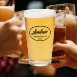 Black Stylised Wedding Groomsman Glass<br><div class="desc">Beer glass for the wedding groomsman that features his name printed in black, stylised script inside a black bordered oval along with wedding year date. A great party supply idea for a bachelor party! Personalise your beer glass by editing and replacing name and date with your own. Available in many,...</div>