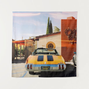 Blue car parked beside brown concrete building in  tapestry