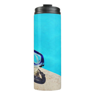 Blue framed swimming goggles near pool at daytime thermal tumbler