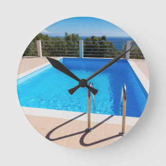 Blue swimming pool with steps at sea round clock