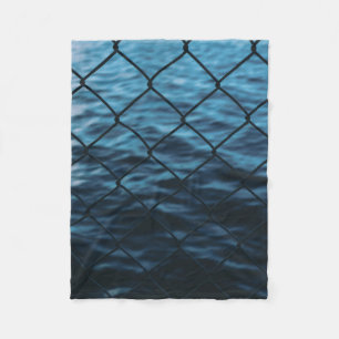 Body of water in front of chain link fence fleece blanket